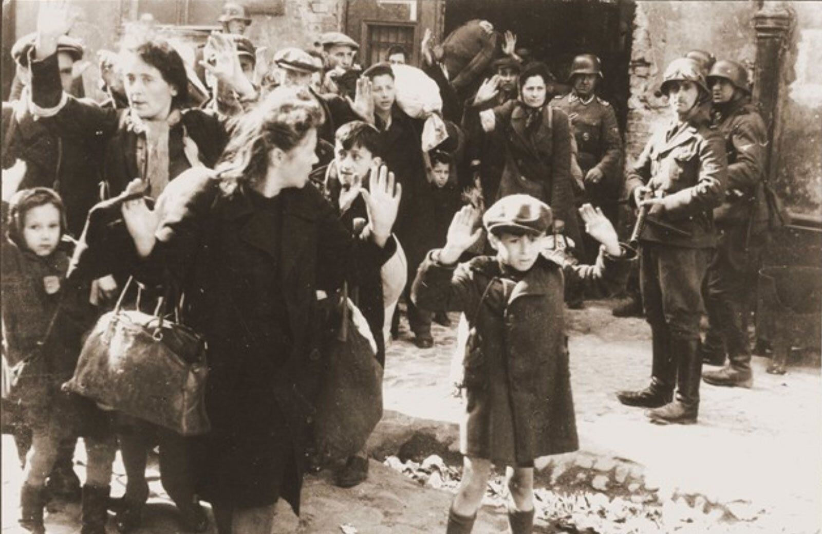 This image shows a 1943 photograph of Nazi soldiers deporting Jews to death camps following the Warsaw ghetto uprising in Warsaw, Poland.